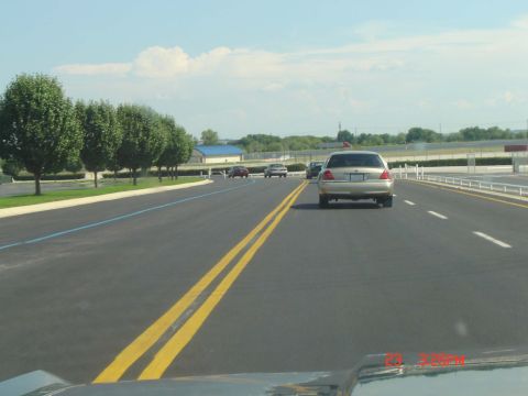 1988 Ford LTD Crown Victoria - A silver Ford Crown Victoria is seen from behind on a highway, with other vehicles in the distance.