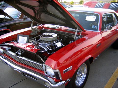 2000 Ford Crown Victoria - A red Nova is displayed with its hood open, revealing a chrome engine and a checkered flag decal on the fender.