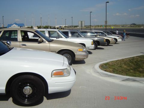 1988 Ford LTD Crown Victoria - Multiple police sedans are parked in a row on a sunny day.