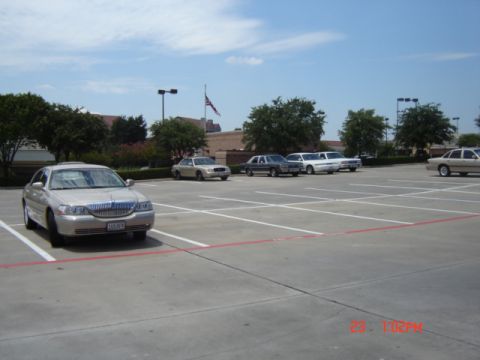 1988 Ford LTD Crown Victoria - A silver Lincoln Town Car is parked in a lot with several other vehicles under a partly cloudy sky.