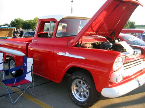 2000 Ford Crown Victoria - A classic red pickup truck with its hood open, chrome accents and a white roof, parked at an outdoor event.