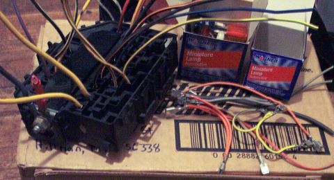 1985 Ford LTD Crown Victoria - A close-up view of an automotive fuse box and associated wiring, alongside packaging for miniature lamps.