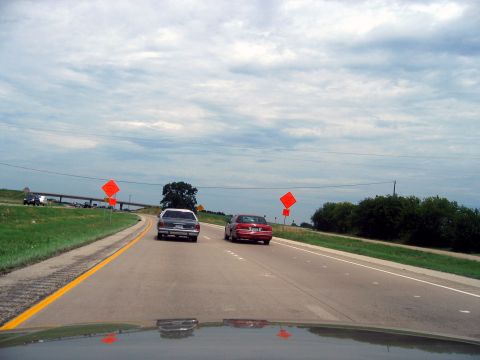 2000 Ford Crown Victoria - A 2000 Ford Crown Victoria is seen from behind on a highway, with another car ahead and construction signs visible.