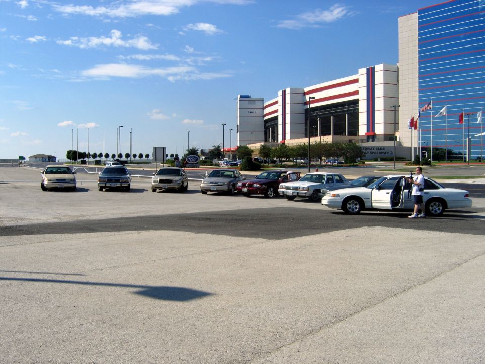 White sedan with open door and person standing next to it, parked in a lot