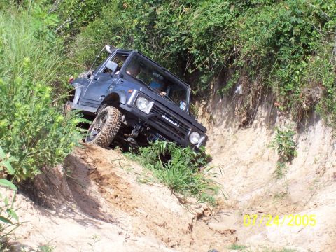 1987 Ford Bronco - Suzuki Samurai tackling challenging terrain on a sunny day.
