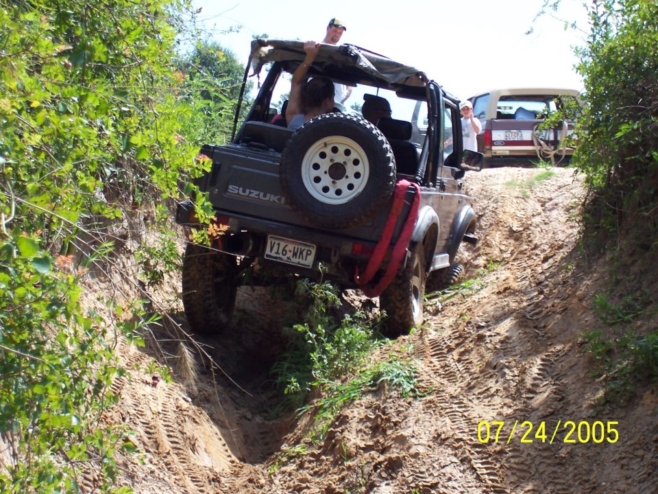 Suzuki Samurai climbing a dirt hill with another SUV behind it