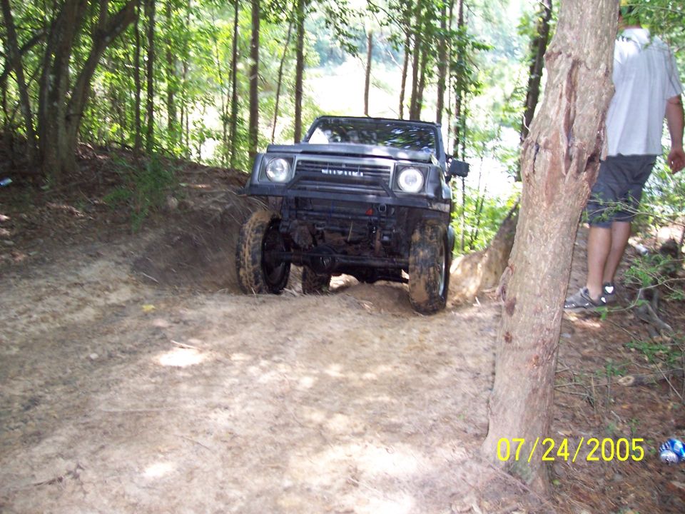 Black Suzuki Samurai driving on a muddy trail in woods. Date stamp 07/24/2005