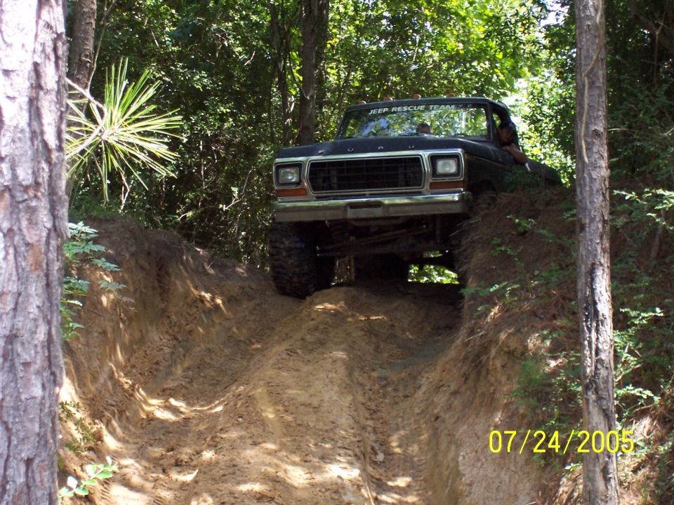Black Ford truck with lifted suspension driving off-road