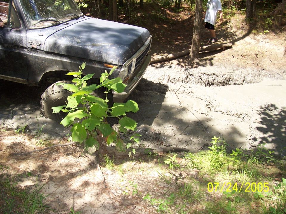1978 Ford Bronco stuck in mud with a person standing in the background
