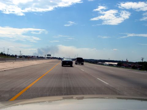 2000 Ford Crown Victoria - A black 2000 Ford Crown Victoria travels down a highway under a partly cloudy sky.