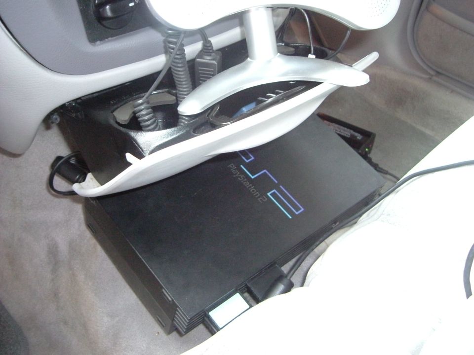 Playstation 2 console mounted in car interior with cables