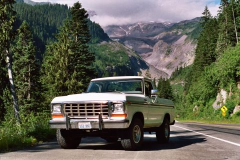 1979 Ford Bronco - A white Ford pickup truck is parked on the side of a road with a mountainous landscape in the background.