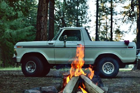 1979 Ford Bronco - A 1979 Ford Bronco sits beside a campfire in a wooded area.