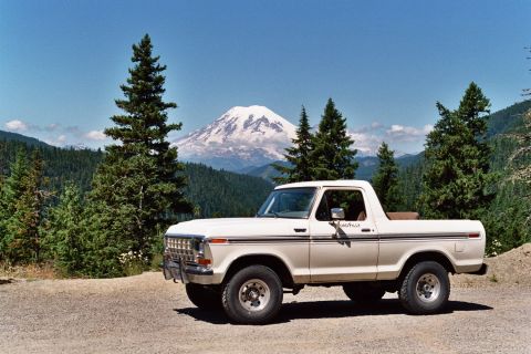1979 Ford Bronco - White 1978 Ford Bronco parked on a gravel road with pine trees and a snow-capped mountain in the background.