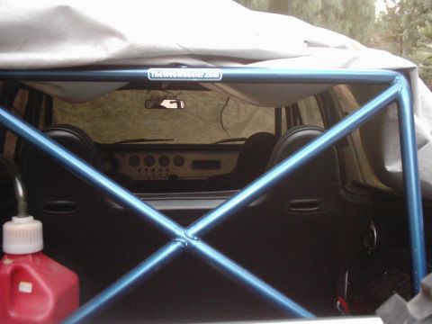 1978 Ford Bronco - The interior of a vehicle is visible, a blue roll cage and black seats, with a red gas can in the foreground.