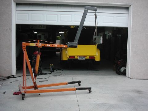 1978 Ford Bronco - A yellow pickup truck bed is being worked on in a garage with an engine hoist overhead.