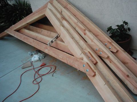 1978 Ford Bronco - Wooden roof trusses are stacked on a concrete surface, with a red extension cord visible nearby.