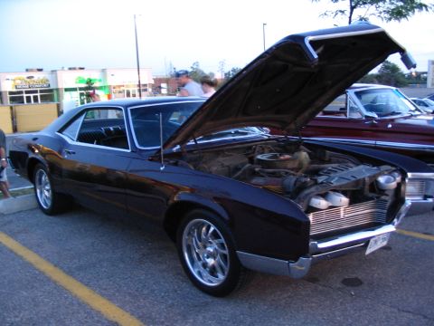 1993 Ford Taurus - A dark coupe is parked with its hood open, revealing the engine bay. Another vehicle is visible to the right.