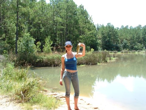 1993 Ford Bronco - A woman proudly displays her catch of the day by the water's edge.