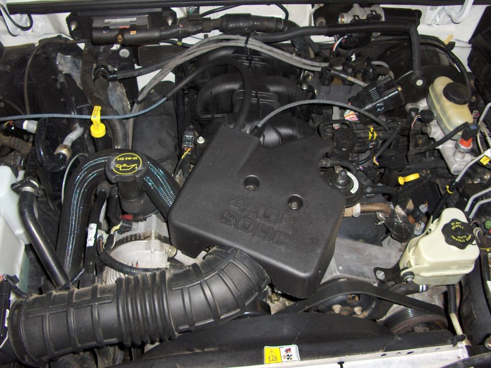 Engine bay showing 4.0L SOHC V6 with black engine cover, intake tube and fluid reservoirs