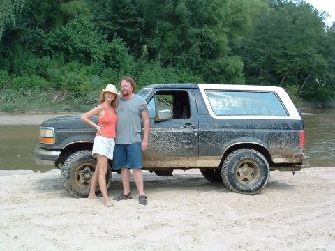 1993 Ford Bronco - Couple poses with a muddy 1993 Ford Bronco near a river.