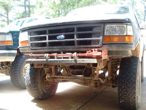 1993 Ford Bronco - The front of a Ford Bronco, showing its grille, headlights, and a winch attached to the bumper. A second vehicle is visible to the left.