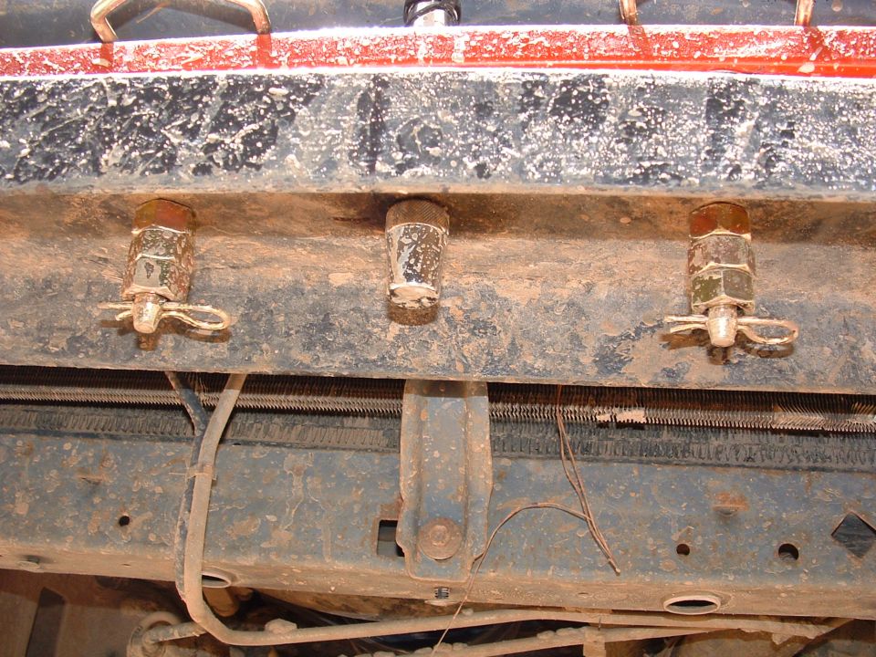 Underside close-up of truck frame crossmember with three plated body-mount bolts