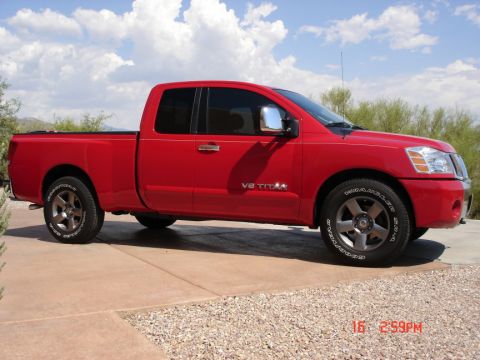 2005 Nissan Titan - A red 2005 Nissan Titan pickup truck is shown from the side, parked outdoors on a sunny day.