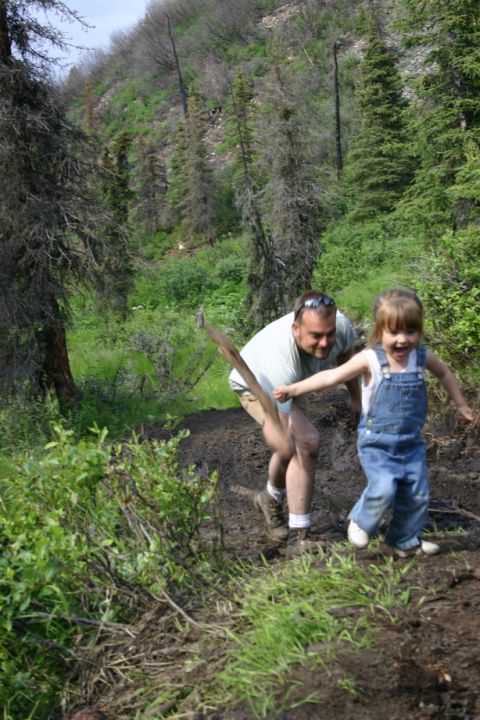 2003 Jeep TJ - Man and child playing on a muddy hillside with trees in the background.