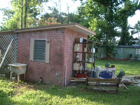 1978 Ford Bronco - Outdoor scene a brick shed with storage shelves and a sink, set in a grassy yard.