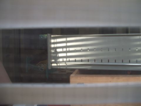 1978 Ford Bronco - A metal grate with horizontal blinds is visible through a window, with shadows cast across it.