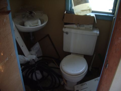 1978 Ford Bronco - Interior view of a cluttered bathroom with plumbing fixtures and storage items.