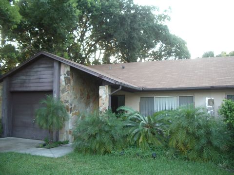 1978 Ford Bronco - Exterior view of a house a garage and overgrown plants in front.