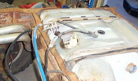1990 Ford Bronco - Close-up view of the fuel tank and pump assembly mounted on a heavily rusted vehicle chassis.