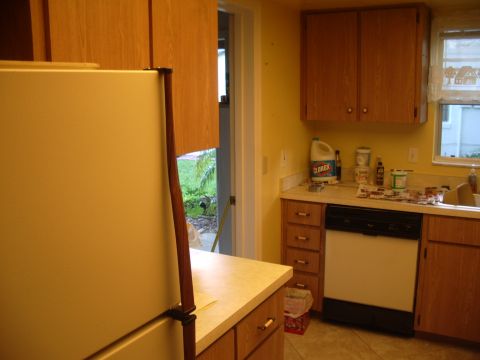 1978 Ford Bronco - A view of a kitchen area a refrigerator, wooden cabinets, a dishwasher, and a countertop with cleaning supplies.