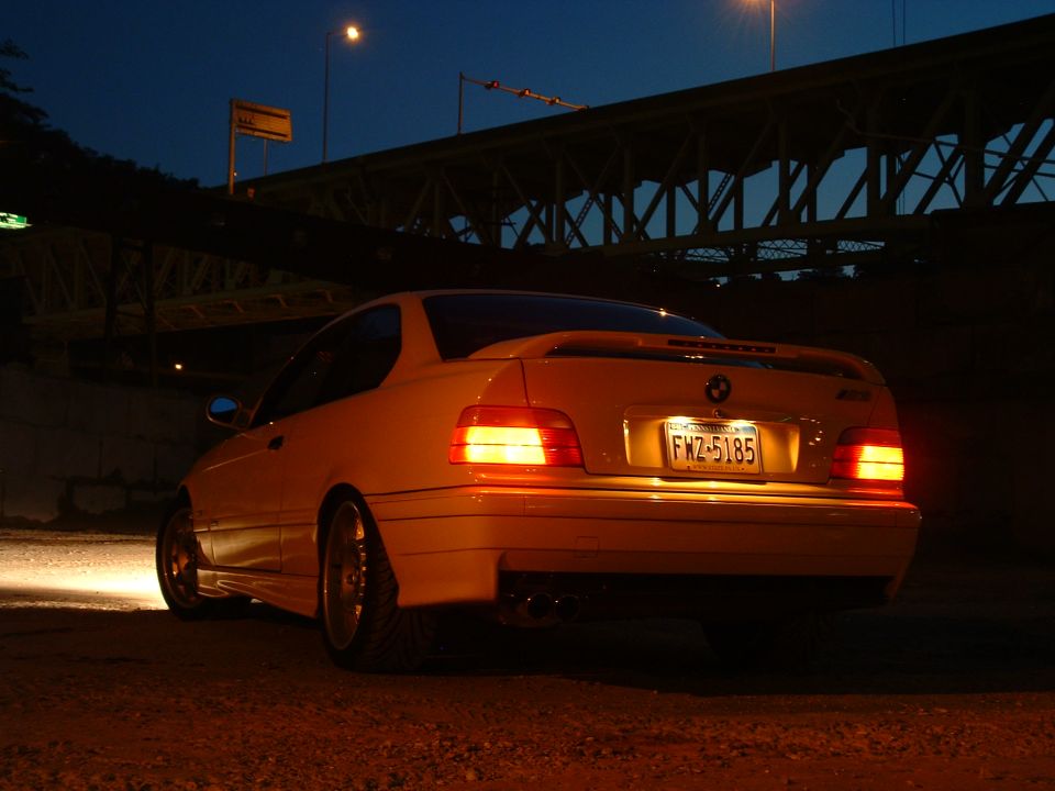 Yellow BMW E36 coupe, rear view, with license plate FWZ-5185. Taillights are illuminated