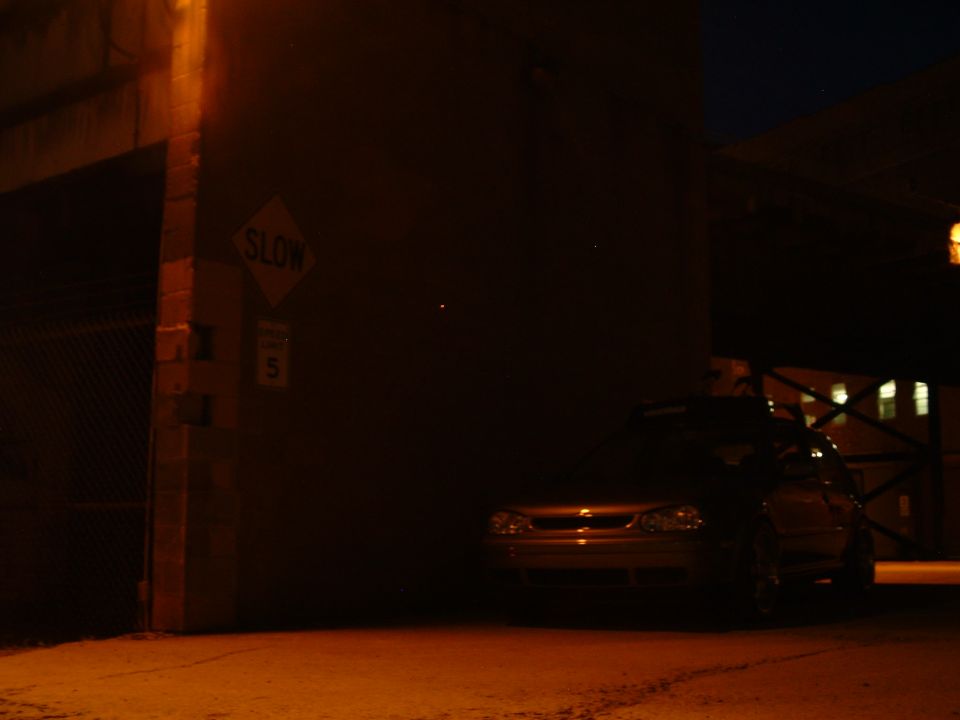 car parked near brick wall at night, slow sign visible