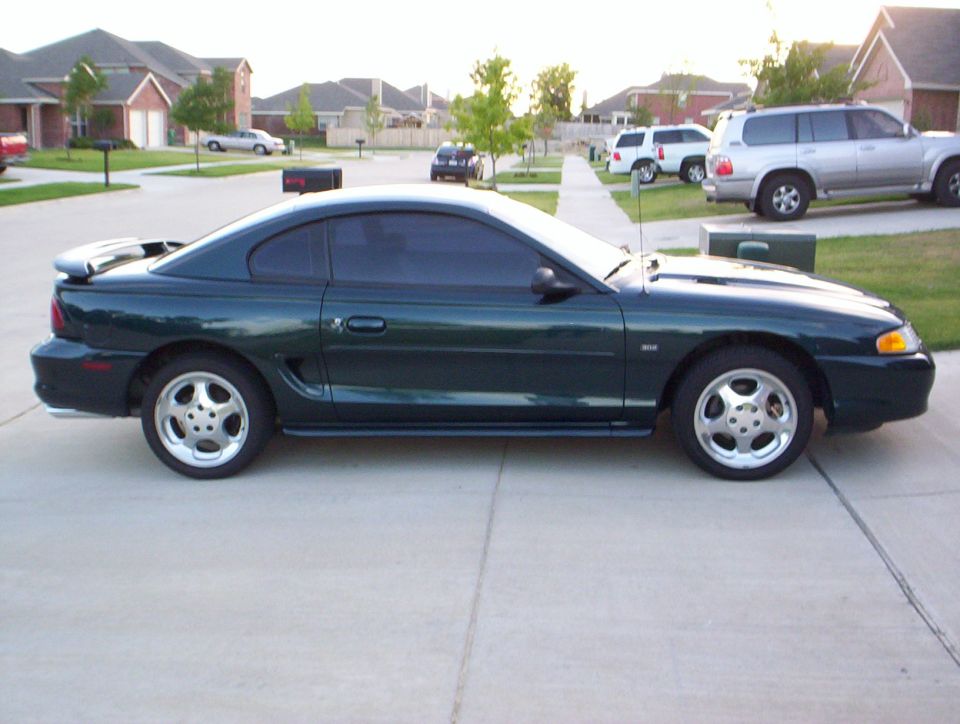 Dark green 1994 Ford Mustang coupe, side view, with a rear spoiler and five-spoke wheels