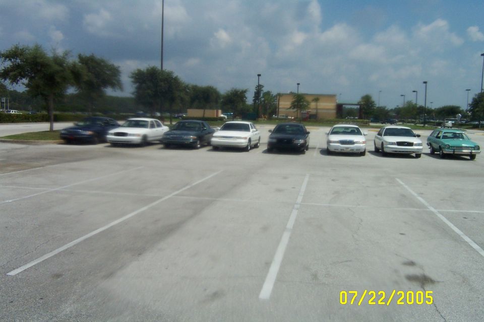 Row of sedans including white Crown Victoria-style cars parked in an open lot, dated 07/22/2005
