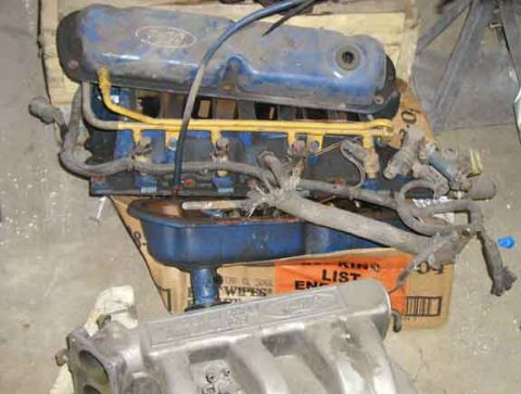 1988 Ford Bronco - Engine components, including a valve cover and intake manifold, are displayed on top of a cardboard box.