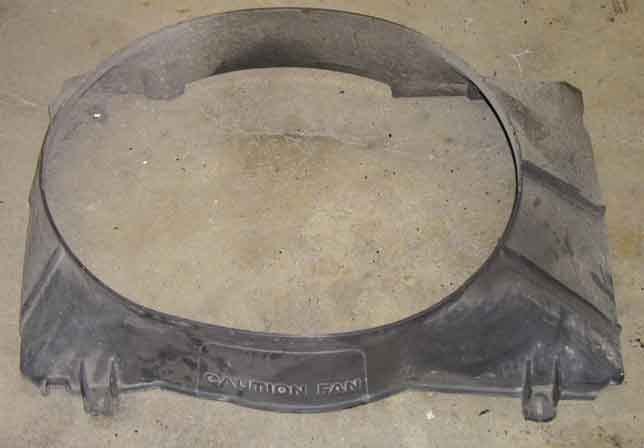 Black plastic radiator fan shroud with "CAUTION FAN" text