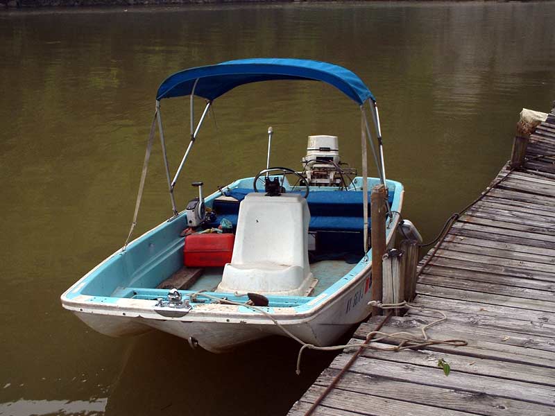 Blue and white boat with outboard motor docked at wooden pier