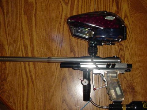 1995 Ford Mustang - A paintball marker is shown with its hopper and clear grip on a wooden table.
