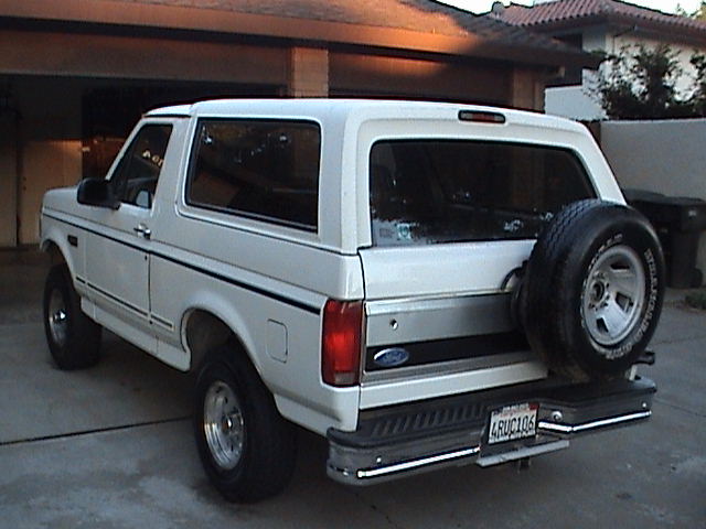 White Ford Bronco, rear view, with spare tire on tailgate, chrome bumper, and license plate 4RUC106