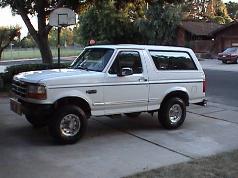 1994 Ford Bronco - This white Ford Bronco is parked in a suburban driveway, with a basketball hoop visible to the left.