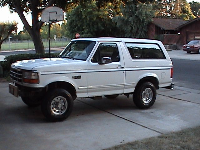 White 1994 Ford Bronco parked in a driveway with a basketball hoop in the background