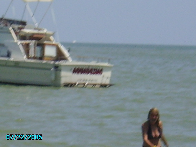 Boat on the water with a person in the foreground. Date stamp 07/22/2005
