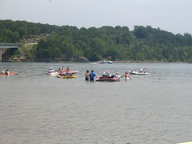 Group of red and yellow flat-deck speedboats anchored in shallow lake water