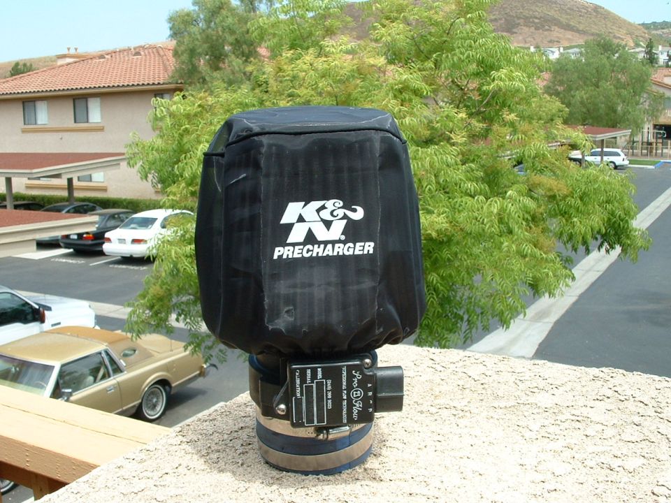 Black K&N Precharger air filter cover with white logo, attached to a metal clamp