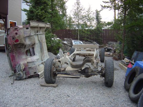 1986 Ford F-150 - The chassis and body of a truck are separated and disassembled in an outdoor setting.